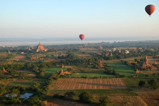 A majestic hot air balloon ascending over Luxor’s ancient temples at sunrise, bathed in golden light.