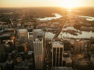 A cinematic drone shot soaring over a bustling cityscape at sunset.