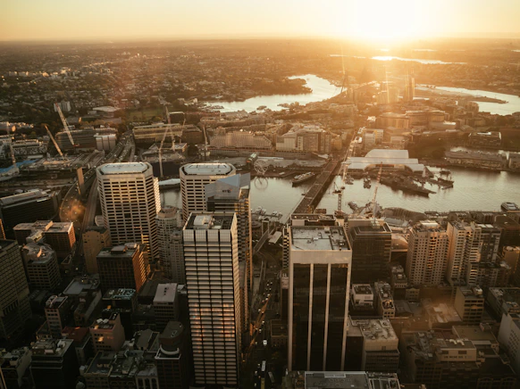 Dynamic shot of a drone flying over a cityscape at sunset, highlighting architectural details.