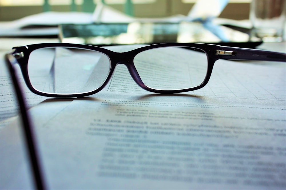 schwarz gerahmte Brille auf weißem Druckpapier