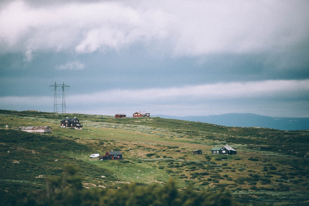 quatro casas no campo de grama verde sob o céu nublado