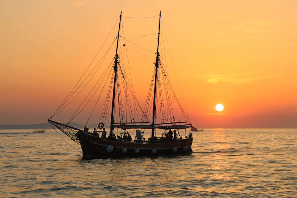 Schwarz-weißes Segelboot im Gewässer bei Sonnenuntergang