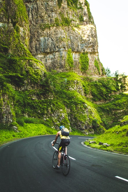 Homem de costas andando de mountain bike por trilha na floresta, simbolizando saúde física
