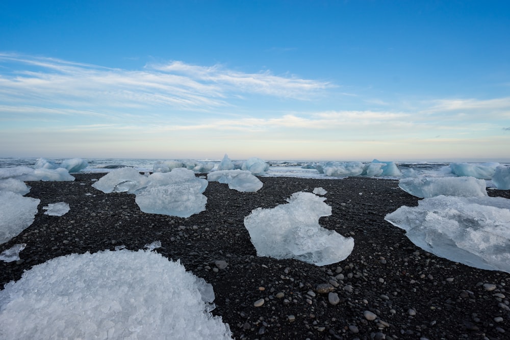 hielo en rocas negras bajo nubes blancas y cielo azul