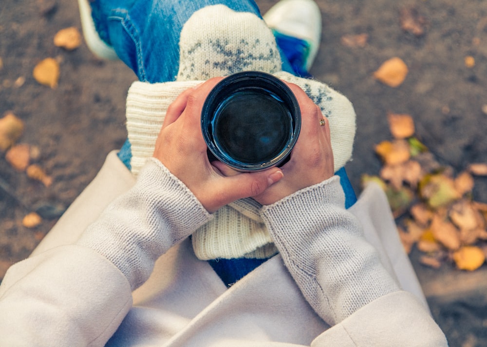 personne tenant une tasse noire sur les genoux de la personne