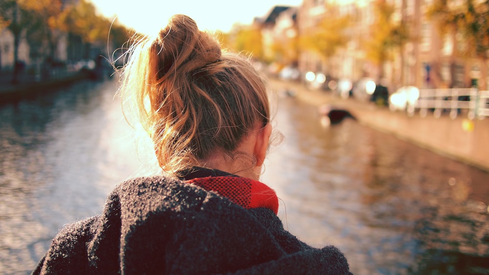 donna che si leva in piedi davanti allo specchio d'acqua