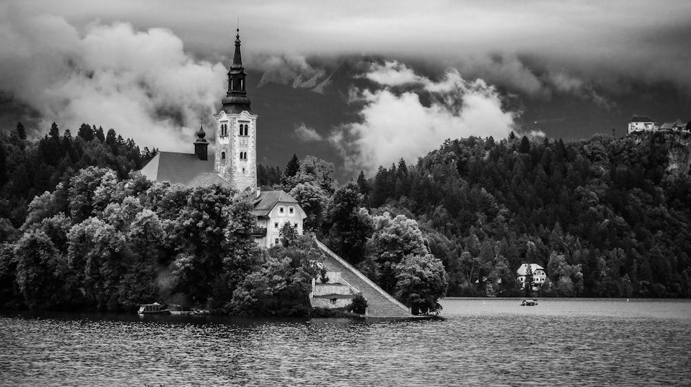 graycale photo of castle near body of water surrounded by trees
