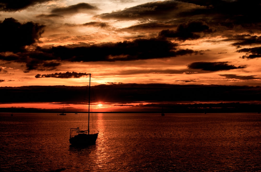 silhouette of boat on sea during golden hour