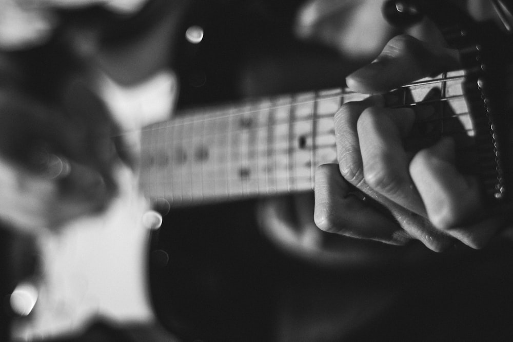 Foto en escala de grises de una persona tocando la guitarra