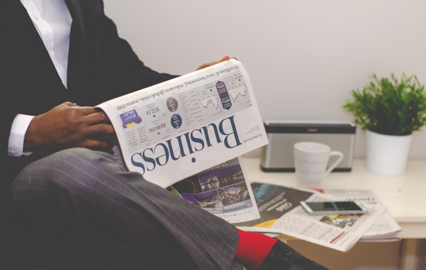 person sitting near table holding newspaper