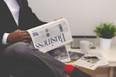 person sitting near table holding newspaper