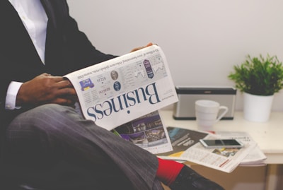 person sitting near table holding newspaper