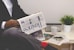 person sitting near table holding newspaper