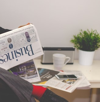 person sitting near table holding newspaper