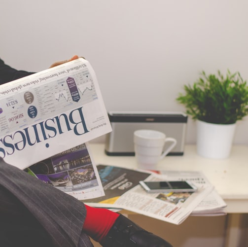 person sitting near table holding newspaper