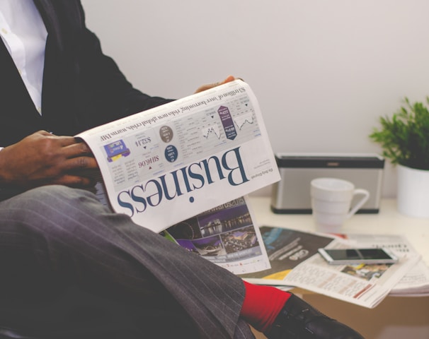 person sitting near table holding newspaper