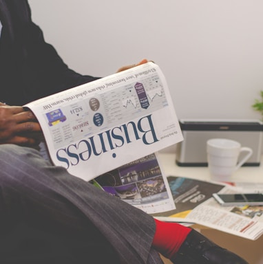 person sitting near table holding newspaper