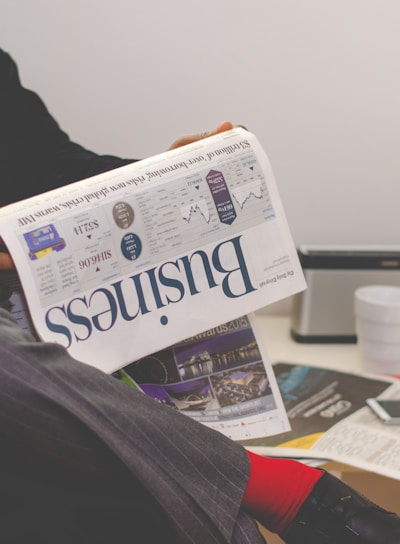 person sitting near table holding newspaper