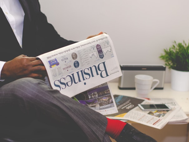 person sitting near table holding newspaper