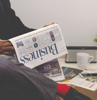 person sitting near table holding newspaper