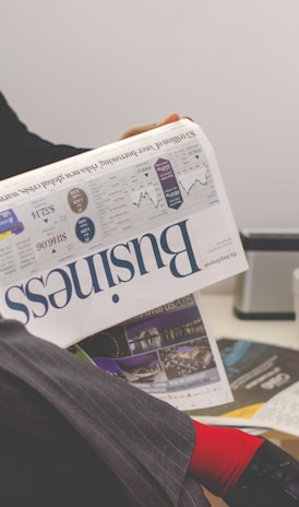 person sitting near table holding newspaper