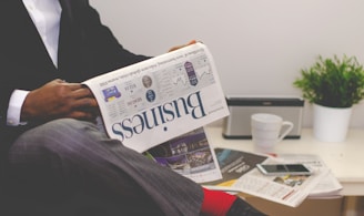 person sitting near table holding newspaper