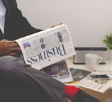 person sitting near table holding newspaper