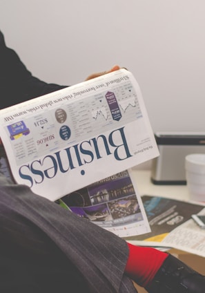 person sitting near table holding newspaper