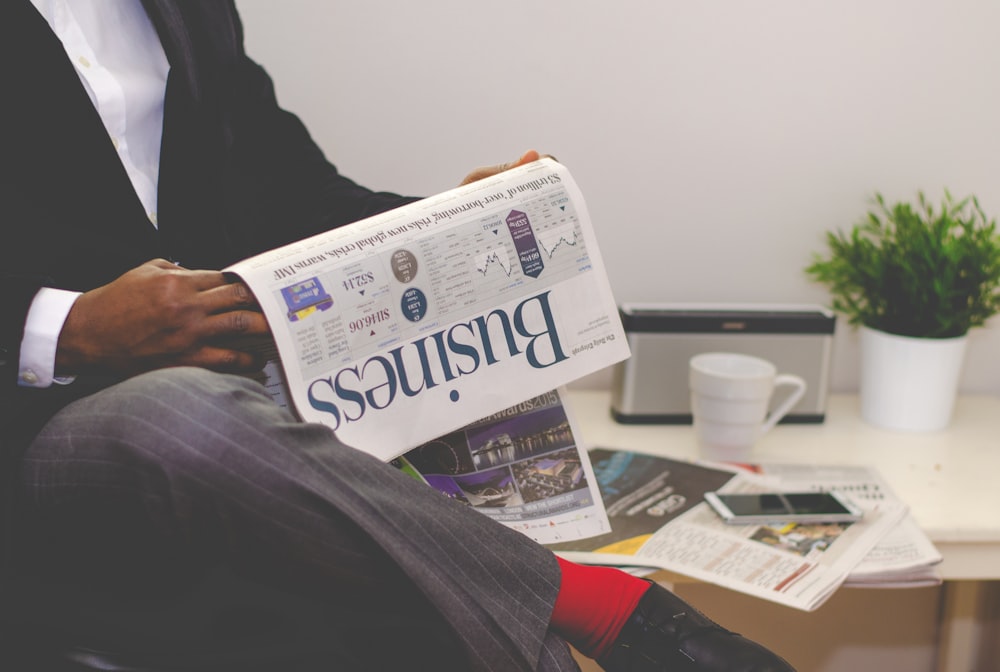 A businessman reading a business newspaper at a table