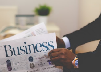 person wearing suit reading business newspaper