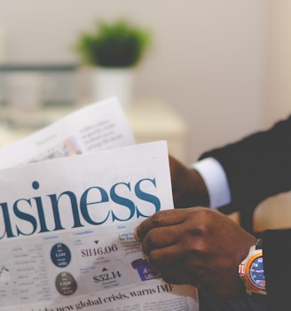 person wearing suit reading business newspaper