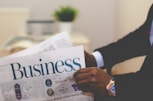 person wearing suit reading business newspaper