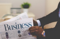 person wearing suit reading business newspaper