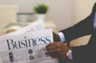 person wearing suit reading business newspaper
