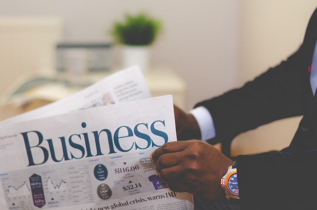 Black man in an expensive suit with an expensive watch reading the business section of a newspaper. 