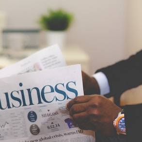 person wearing suit reading business newspaper