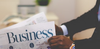 person wearing suit reading business newspaper