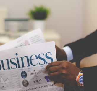 person wearing suit reading business newspaper