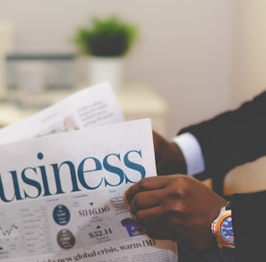 person wearing suit reading business newspaper