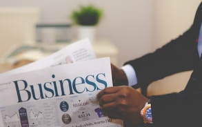 person wearing suit reading business newspaper