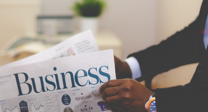 person wearing suit reading business newspaper