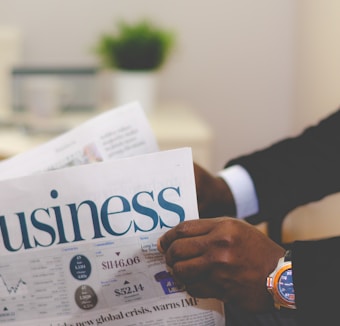 person wearing suit reading business newspaper