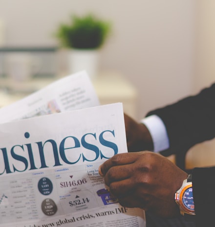 person wearing suit reading business newspaper