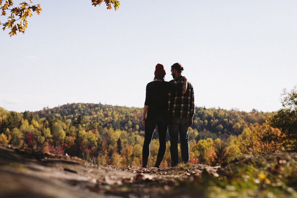 couple standing in front green trees field