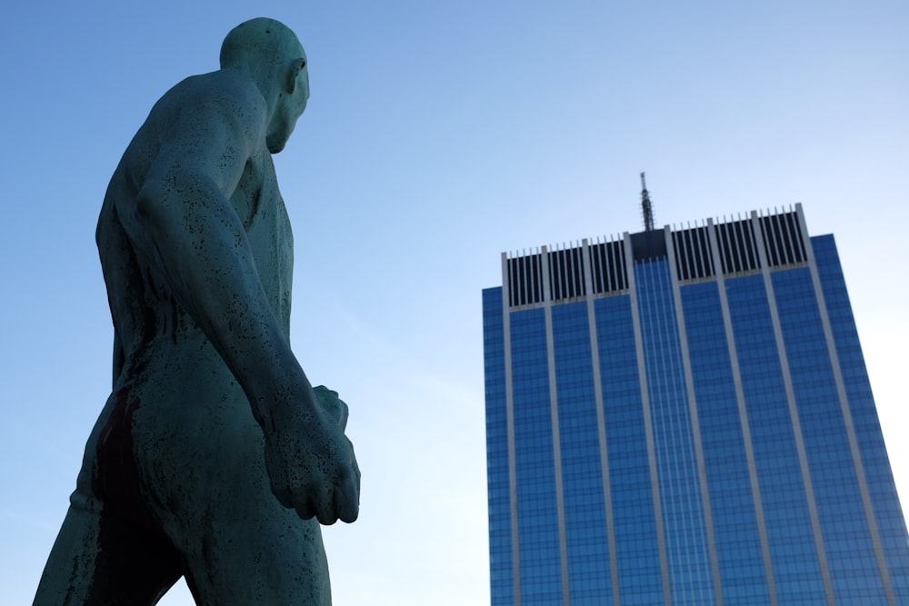 naked man statue in front high-rise building