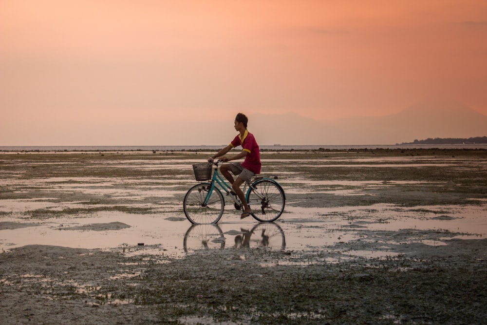 person in red top riding blue city bicycle