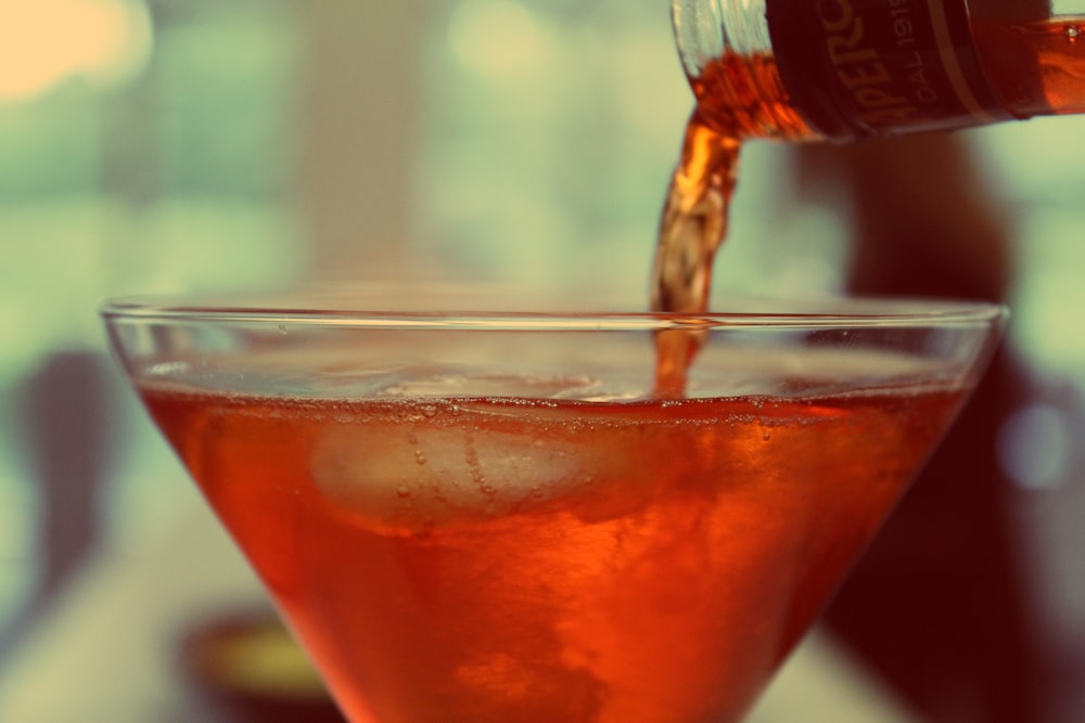liquide rouge versé sur un verre à martini transparent