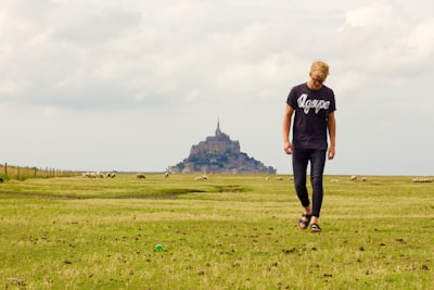 person in b lack crew-neck shirt walking on green path grass awesome teams background