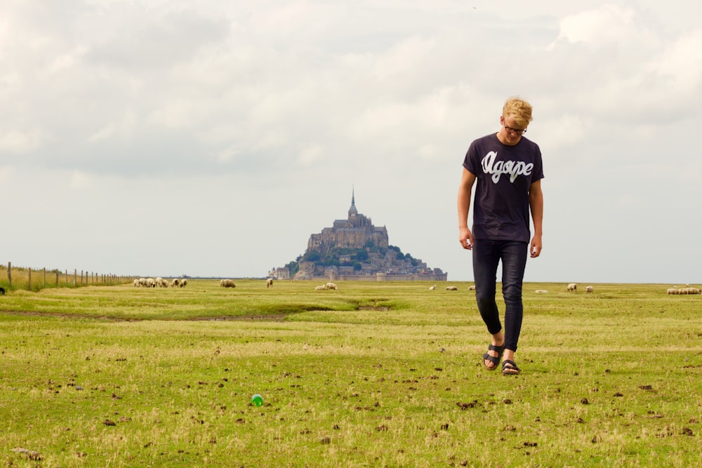 person in b lack crew-neck shirt walking on green path grass