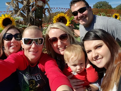 A cozy family posing happily in front of a vibrant autumn-themed selfie wall with pumpkins and colorful leaves.